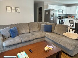 A living room with a sectional sofa, a wooden coffee table, and a remote control.