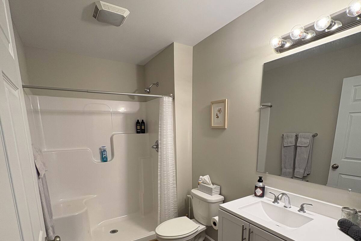 A bathroom with a shower, toilet, sink, and vanity.