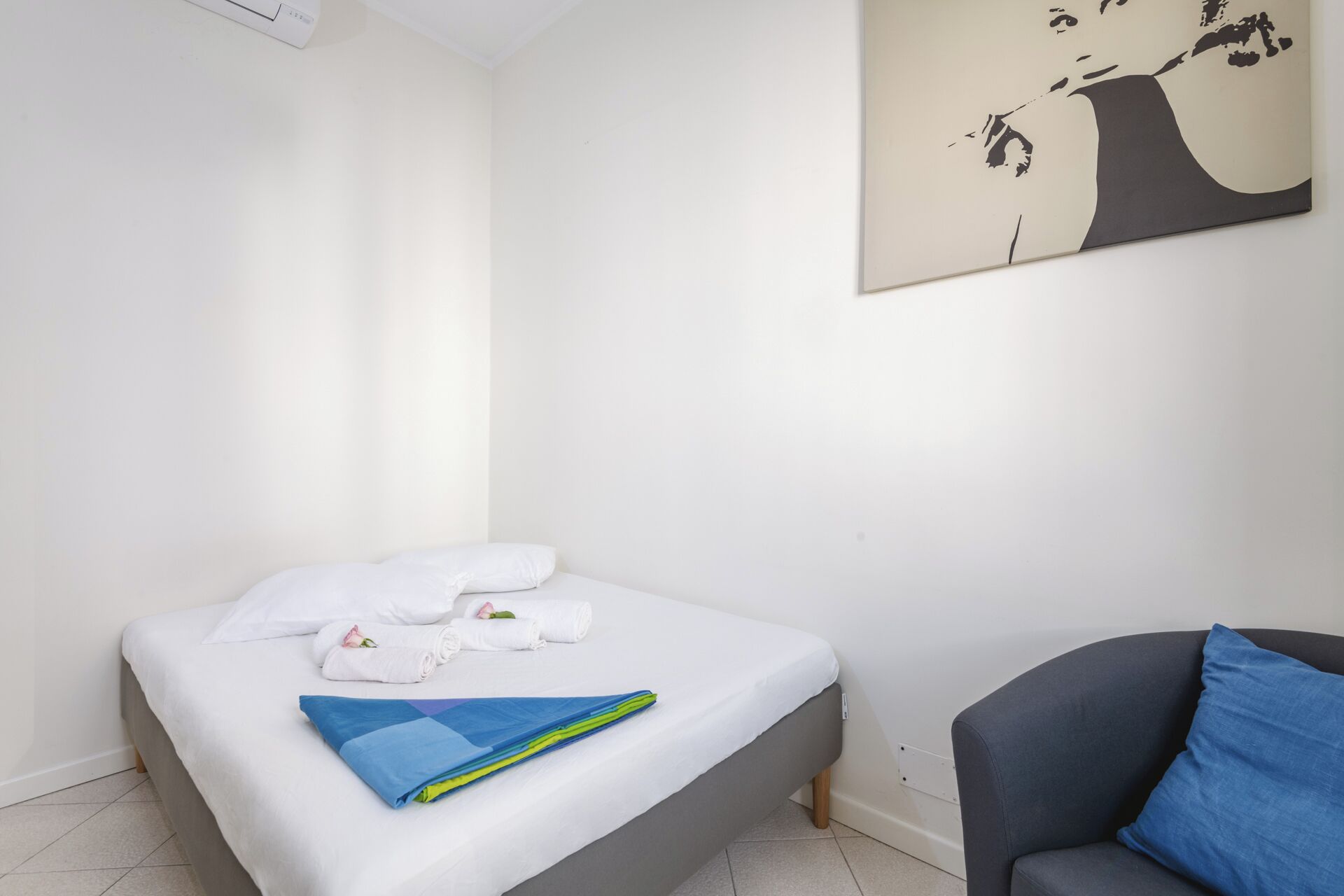 Hotellihuone, jossa on sänky, tuoli ja seinätaideteos.