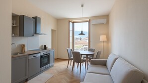 Une cuisine compacte avec des meubles gris, un coin repas avec une table ronde et des chaises, et un canapé.