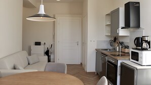 Une cuisine moderne équipée d’un four à micro-ondes, d’une machine à café et d’un évier. Un coin repas avec une table et des chaises est également à disposition.