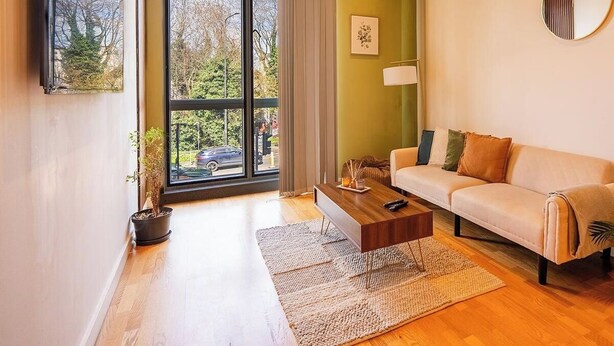 Una sala de estar moderna con sofá, mesa de centro y un ventanal con cortinas.