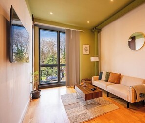 Una sala de estar moderna con sofá, mesa de centro y un ventanal con cortinas.
