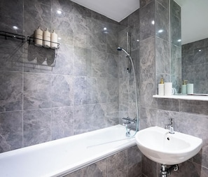Un baño moderno con bañera, lavamanos y ducha.