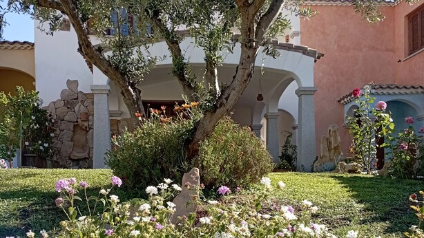 Un jardin où l’on peut admirer une grande variété de fleurs, avec une statue de pierre en premier plan.