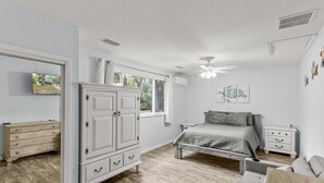 A bedroom with a bed, a dresser, a nightstand, and a ceiling fan.
