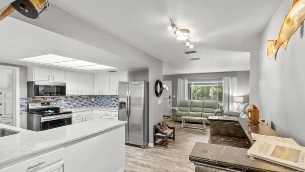 A modern kitchen with white cabinets, stainless steel appliances, and a large island.