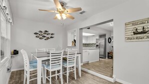 A dining area with a white table and chairs, a ceiling fan, and a wall-mounted fish decoration.