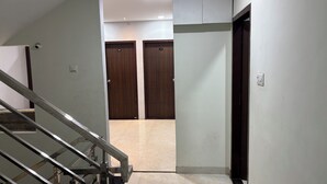 A hallway with a metal staircase, two wooden doors, and a light-colored tiled floor. - Hotel Fortune (Indore)