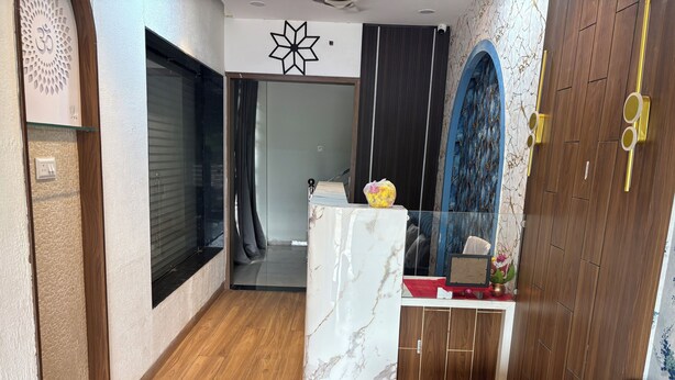 A modern interior with a marble reception desk, wooden flooring, and a blue sofa. - Hotel Fortune (Indore)