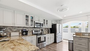 A modern kitchen with white cabinetry, stainless steel appliances, and a granite countertop.