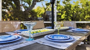 A dining table set with blue plates, clear glasses, and a white dish with yellow accents.