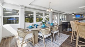 A dining area with a large table, chairs, and a television.