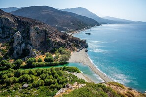 Paisagem costeira com praia, falésias rochosas e vegetação.