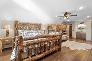 A rustic bedroom with a wooden bed frame, a ceiling fan, and a wooden nightstand with a lamp. - Grand Moose Lodge – Private Pool, Theater, Hot Tub Retreat & Outdoor Cabana (Hollister)
