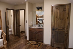 A hallway with wooden doors, a kitchen area with a granite countertop, and a bathroom visible in the background. - Grand Moose Lodge – Private Pool, Theater, Hot Tub Retreat & Outdoor Cabana (Hollister)