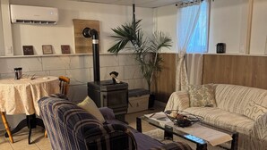 A living room with a sofa, a coffee table, a dining table, and a kitchen area with a stove.
