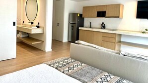 A modern kitchen with wooden cabinets, a built-in oven, and a flat-screen TV. - Modern Studio, Pool, WiFi, min Sea and 5th Ave. (Playa del Carmen)