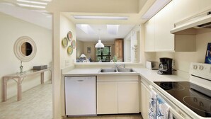 A modern kitchen with a dishwasher, stove, and sink. There is a dining area with a table and chairs.