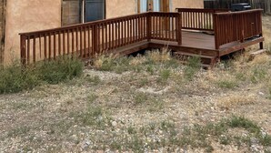 A rustic building with a wooden deck and a single door.