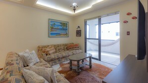 Una sala de estar con un sofá estampado, una mesa de centro y un ventanal con vistas al exterior.
