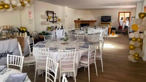 A dining area with round tables set for a formal event, white chairs, and a fireplace in the background. - Rural house torre chica located in frailes jaen in the middle of nature (frailes)