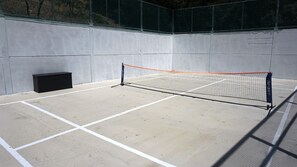 Pista de tenis interior con red, líneas marcadas y un altavoz negro en la esquina.