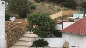 A residential area with a staircase leading to a white building with a red roof. There is a tree in front of the building, and a fence with a patterned design. - Rural house torre chica located in frailes jaen in the middle of nature (frailes)