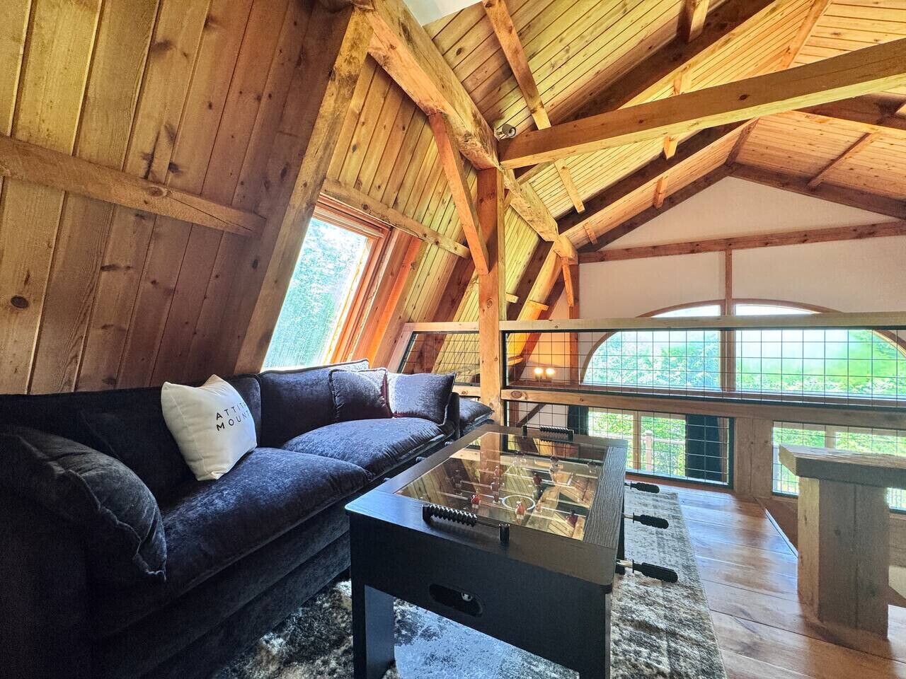 A cozy room with a wooden ceiling, a sofa with a pillow, and a foosball table.
