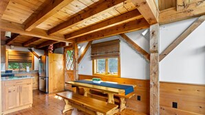 Ein rustikales Blockhaus-Interieur mit einem Holzesstisch, einer Küchenzeile und einem großen Fenster.