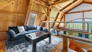 Ein gemütlicher Loft-Raum mit Holzboden, einer Couch, einem Glastisch und Blick durch ein Fenster.
