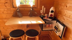 A compact wooden cabin with a small kitchenette, two stools, a refrigerator, and a window with a view of greenery. - Chalet 2: Breakfast optional  (Aouste-sur-Sye)