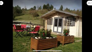A small cabin with a wooden deck, red chairs, and planters with flowers. - Chalet 2: Breakfast optional  (Aouste-sur-Sye)