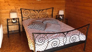 A wooden cabin bedroom with a bed, two nightstands, and a decorative wall piece. - Chalet 2: Breakfast optional  (Aouste-sur-Sye)
