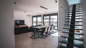 Eine moderne Küche mit Essbereich, großen Fenstern und einer Treppe.