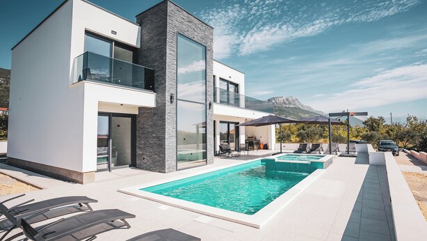 Ein modernes, zweistöckiges Haus mit Swimmingpool, Außenbereich und Bergblick.