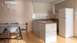 A modern kitchen with a marble island, a built-in refrigerator, and pendant lighting.