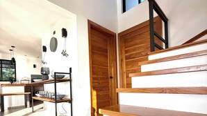 A modern kitchen with a dining area, wooden staircase, and a large window. - Costa Rica dream: ocean view, infinity pool, surrounded by nature (Puntarenas Province)