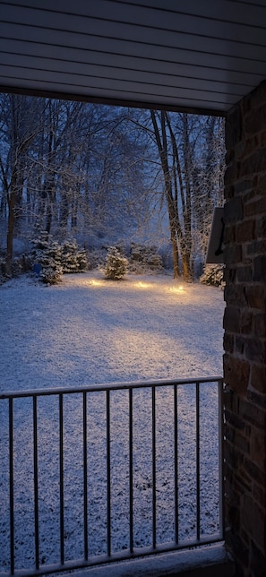 A snow-covered yard with a brick wall and metal railing. - Chez Parrain (Sprimont)
