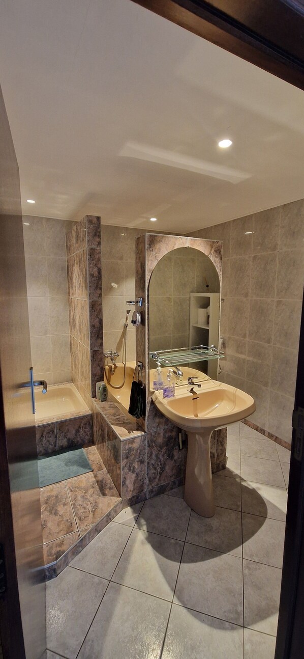 Un baño con bañera, lavamanos y espejo.