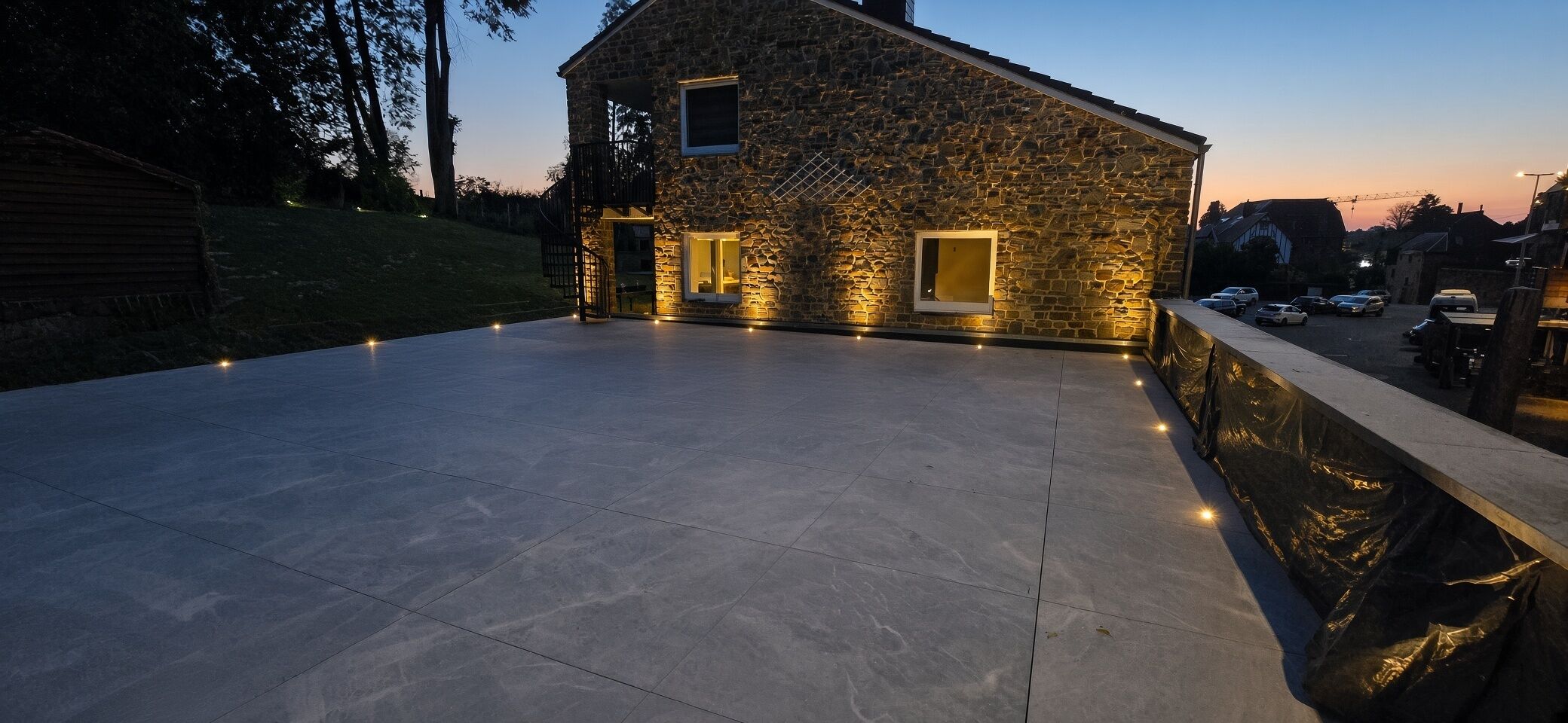 A stone house with a flat roof and a paved patio area.