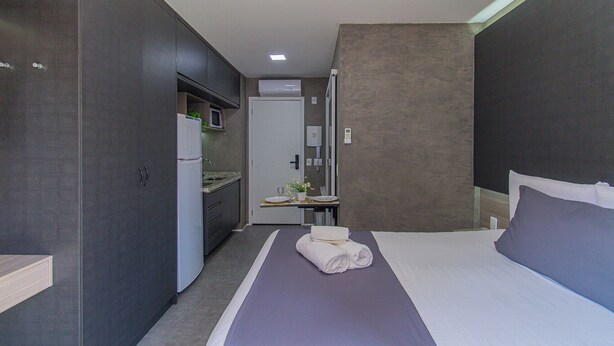 A modern hotel room with a bed, a small kitchenette, and a bathroom. - Loft a 10min do Metr com Academia na Vila Mariana (São Paulo)