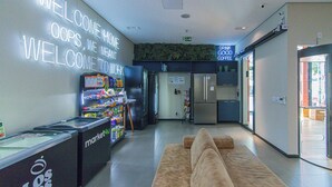 A modern lobby with a 'Welcome Home' sign, a coffee machine, a refrigerator, and a vending machine. - Loft a 10min do Metr com Academia na Vila Mariana (São Paulo)