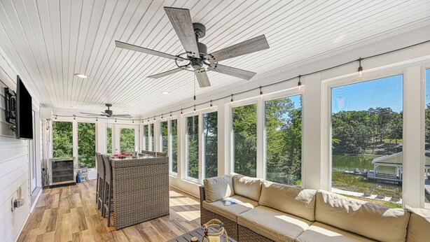 A spacious sunroom with a ceiling fan, large windows, a sofa, and a table.