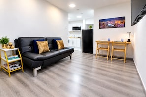 Ein modernes Wohnzimmer mit einer schwarzen Ledersofa, einem kleinen Holztisch und einem Bücherregal.