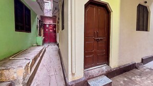Une ruelle étroite, avec une porte marron au fond, un mur vert à gauche et un mur beige à droite.