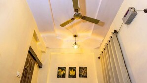 Un couloir doté d’un ventilateur de plafond, d’un luminaire et de trois œuvres d’art accrochées au mur.