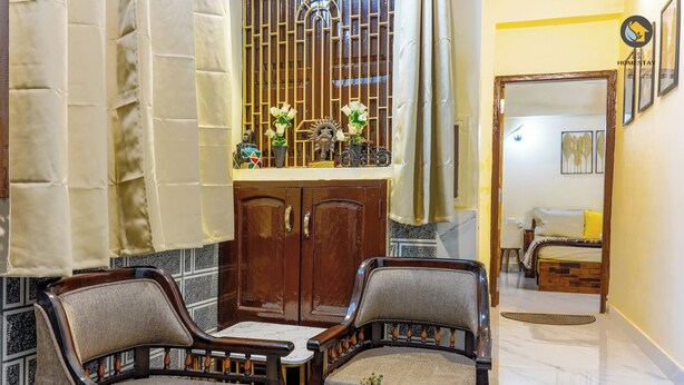 Une pièce comprenant deux fauteuils rembourrés, une petite table et un meuble contenant des objets décoratifs.