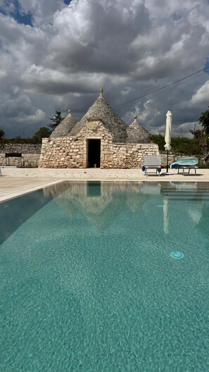 Un edificio de piedra con una piscina al frente.