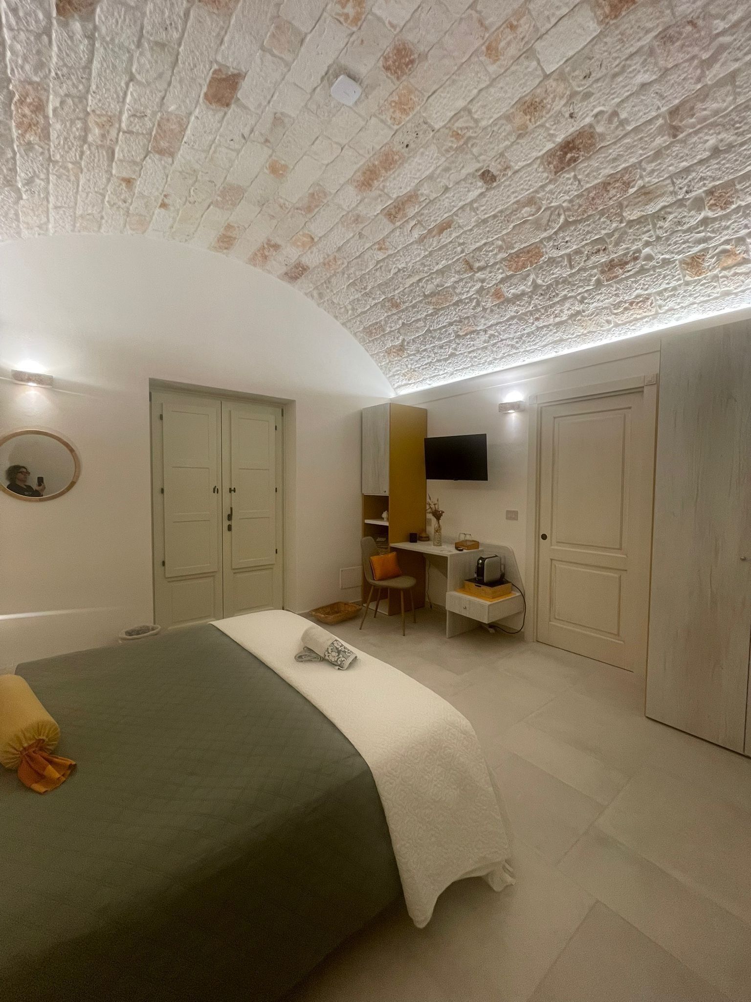 A bedroom with a bed, a desk, a chair, and a TV.